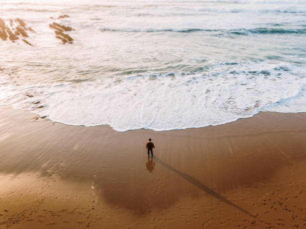 istock Person standing on a beach at sunset 1376042807