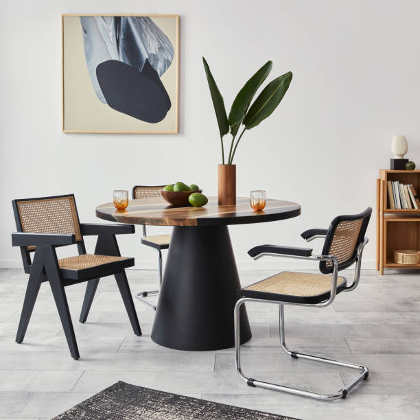 istock Stylish composition of dining room interior with design table, modern chairs, decoration, tropical leaf in vase, fruits, bookcase, abstract mock up paintings and elegant accessories in home decor. 1376054926