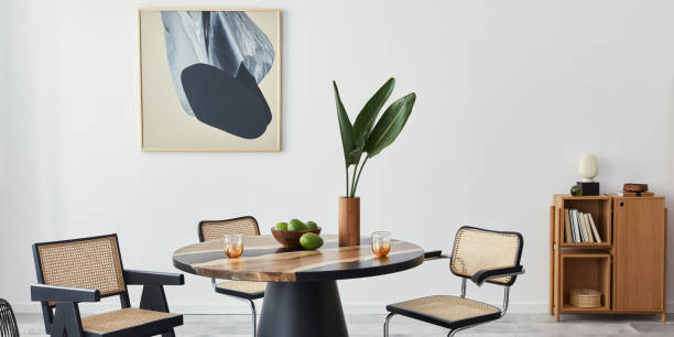 istock Stylish composition of dining room interior with design table, modern chairs, decoration, tropical leaf in vase, fruits, bookcase, abstract mock up paintings and elegant accessories in home decor. 1376054929