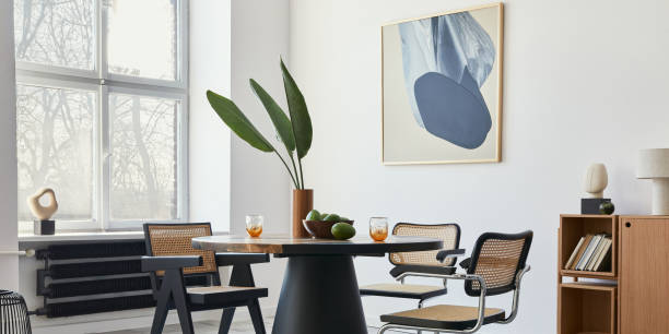istock Stylish composition of dining room interior with design table, modern chairs, decoration, tropical leaf in vase, fruits, bookcase, abstract mock up paintings and elegant accessories in home decor. 1376054953