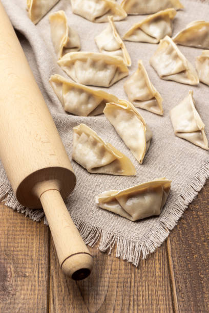 istock Rolling pin and raw gyoza dumplings on linen napkin. 1376066310
