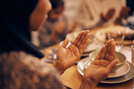 Primer plano de una mujer musulmana negra rezando con su familia en la mesa del comedor. photo