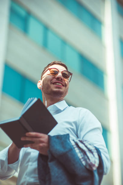 istock Stylish young lawyer write in notebook while talking with somebody on headphones 1376090829