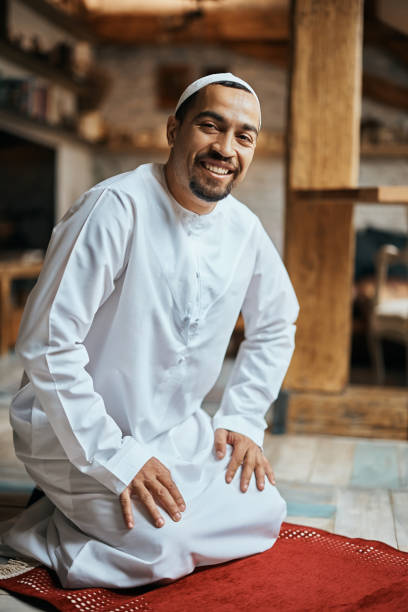 istock Happy Muslim on kneeling on a prayer mat at home and looking at camera. 1376091177