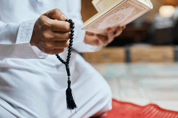 istock Close-up of Muslim man using misbaha beads while reading from Koran at home. 1376091930