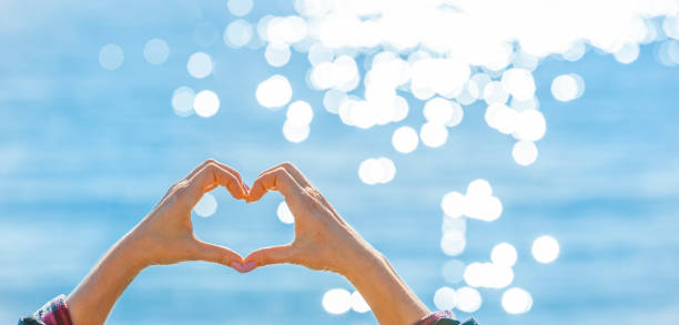 istock A hand forms a heart in front of glittering water 1376091991
