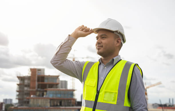 istock Asian engineer man or architect looking forward with white safety helmet in city construction site . Standing on rooftop building construction at capital. 1376103397