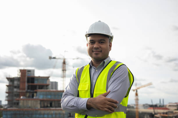 istock Asian engineer man or architect looking forward with white safety helmet in city construction site . Standing on rooftop building construction at capital. 1376103524