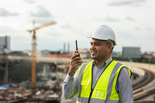 istock Asian engineer handsome man or architect use radio communication with white safety helmet in city construction site . Standing on rooftop building construction at capital. 1376103529