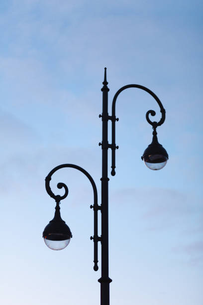 istock A double black street lamp with two (2) light bulbs against cloudy blue sky 1376103599