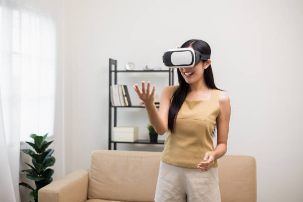 istock Young asian woman put on vr glasses into virtual simulated world. Future technology digital cyber universe. Person Enjoying an Experiences of Virtual World. 1376103699