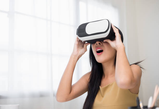 istock Young asian woman put on vr glasses into virtual simulated world. Future technology digital cyber universe. Person Enjoying an Experiences of Virtual World. 1376104034