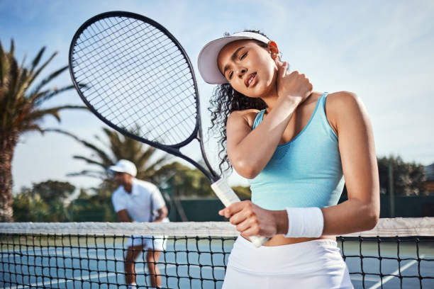 foto de una atractiva joven que sufre una lesión en el cuello durante la práctica de tenis con su compañero de equipo - tennis couple women men fotografías e imágenes de stock