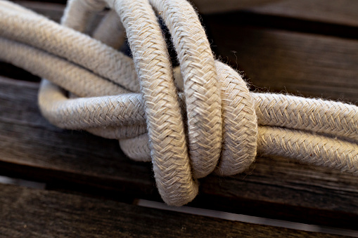 Above shot of hiking rope tied in a knot against a wooden background in studio. Sheet bend knot, A knot for every situation. Strong rope to secure safety while mountain climbing or extreme sports