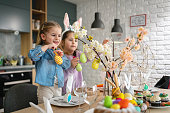 Playful Caucasian sisters, decorating the table for an Easter lunch