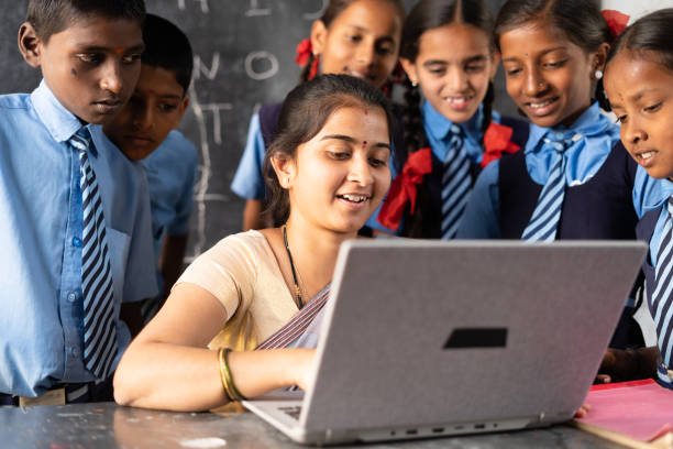 Young indian teacher teaching on laptop with school uniform students at classroom - concept of development, technology and digital education Young Indian teacher teaching on laptop with school uniform students at classroom - concept of development, technology and digital education indian teacher stock pictures, royalty-free photos & images