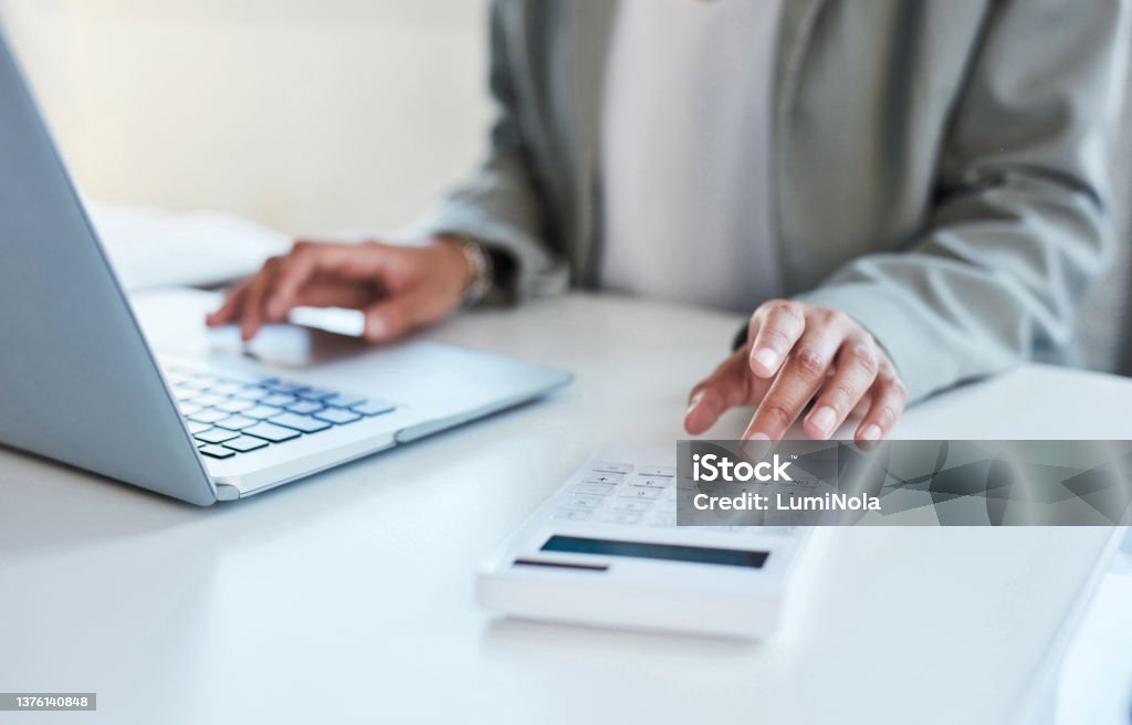 Closeup shot of an unrecognisable businesswoman using a calculator and laptop in an office Checking some digits Paycheck Stock Photo