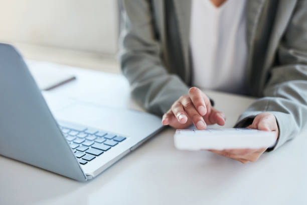 closeup shot of an unrecognisable businesswoman using a calculator and laptop in an office - employment document imagens e fotografias de stock