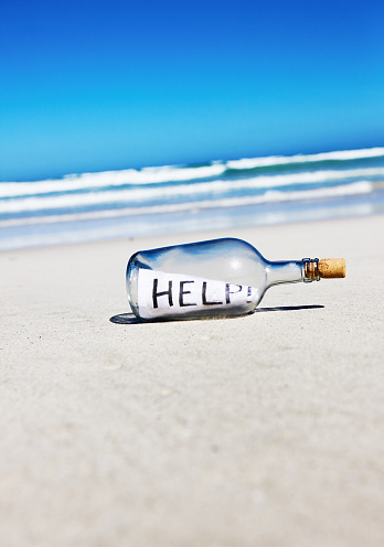 HELP, says text on message inside a castaway's bottle washed up on a remote beach in beautiful summer weather.