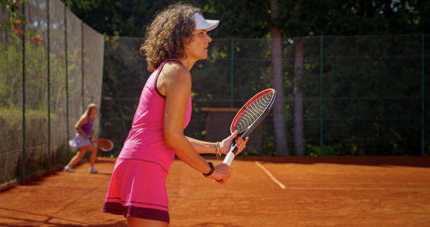 Woman playing tennis Senior woman playing tennis on clay court during sunny day. older women short skirts stock pictures, royalty-free photos & images