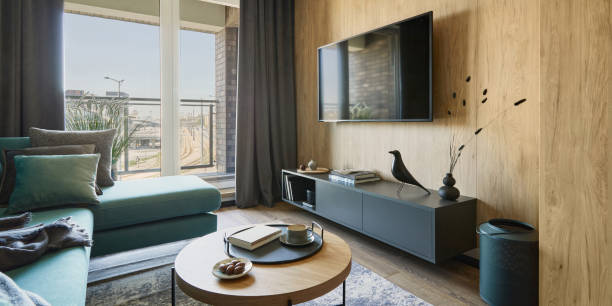 istock Creative composition of modern living room interior in small apartment. Eucalyptus sofa, designed coffee table, black commode and personal accessories. Big windows with a big city view on. Template. 1376168462