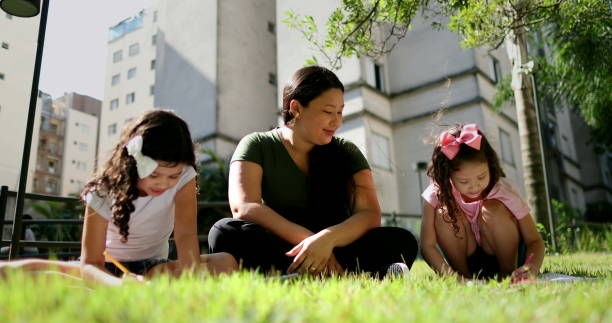 istock Asian mother helping daughters with homework outside at park 1376192982
