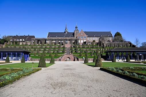 Flowers in the garden park of Belvedere in Weimar, Germany\nA beautiful country house with a vibrant flower garden in full bloom under a clear blue sky, depicting rural tranquility.