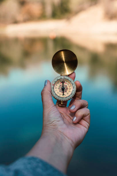 istock Unrecognizable person holding a compass at a lake 1376220386