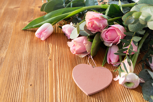 Pink bouquet with heart shape on wood. Background for mother's day greetings. Close-up with short depth of field and space for text.