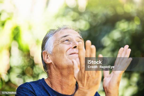 Serious Man Looks Imploringly Upward To Heaven As If Praying Outdoors In A Garden Stock Photo - Download Image Now