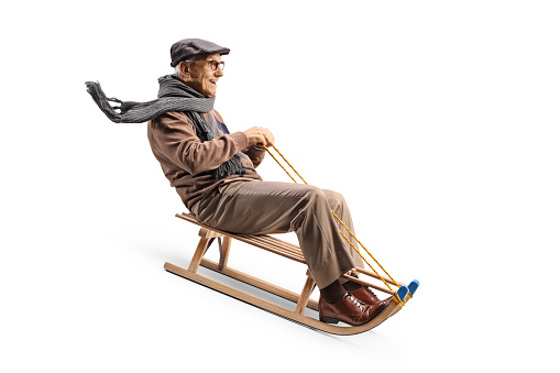 Elderly man riding on a wooden sleigh isolated on white background