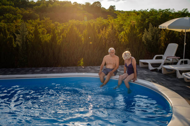 istock Senior couple sitting at the poolside 1376314385