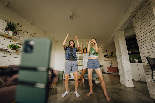 Photo of young influencers recording challenge videos for social media accounts; friends participating in the viral video challenge on the Internet.