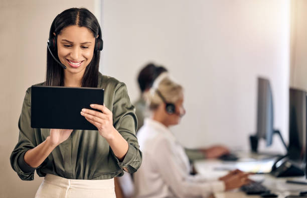 istock Shot of a young call centre agent using a digital tablet while working in an office with her colleagues in the background 1376355666