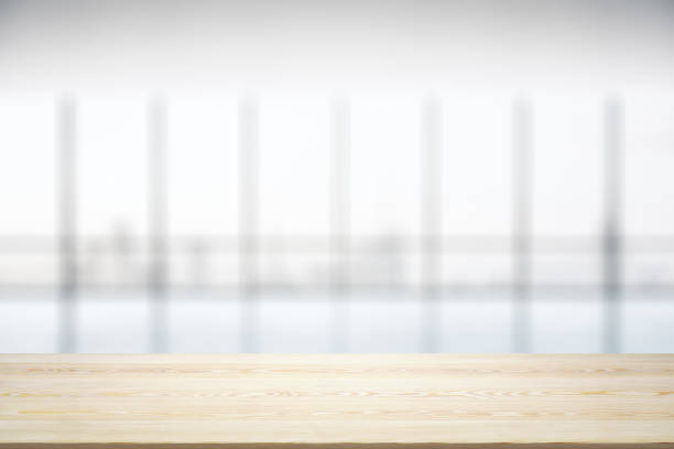 istock Empty wooden table with light sunny office interior with large window on background, mock up 1376361712