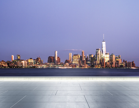Empty concrete quay on the background of a beautiful blurry Manhattan skyline at twilight, mock up