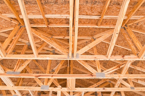 Unfinished wooden roof beam construction of a new house. The frame construction is planked with OSB panels. This image is part of a series.