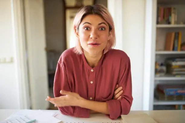 Portrait of cheerful enthusiastic young woman having amazed facial expression, gesturing emotionally, taking about her ideas and plans with colleagues via virtual webcam video conference chat