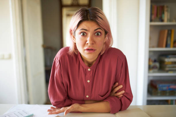 istock Strict indignant young female teacher sitting at table in her apartment, teaching language online using webcam, telling off student because of unfinished homework. Distant learning and education 1376381847