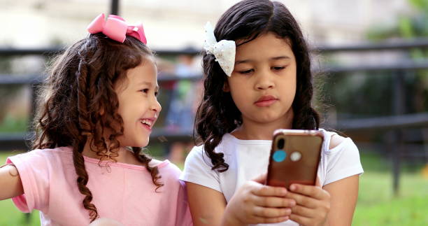 istock Cute small girls looking at cellphone outside 1376383459