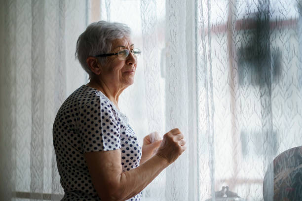 istock Senior Woman standing in front of a window 1376405161