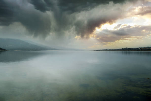 stormy landscape on mountain lake with clouds breaking open by the sun in Lozoya, Community of Madrid, Spain