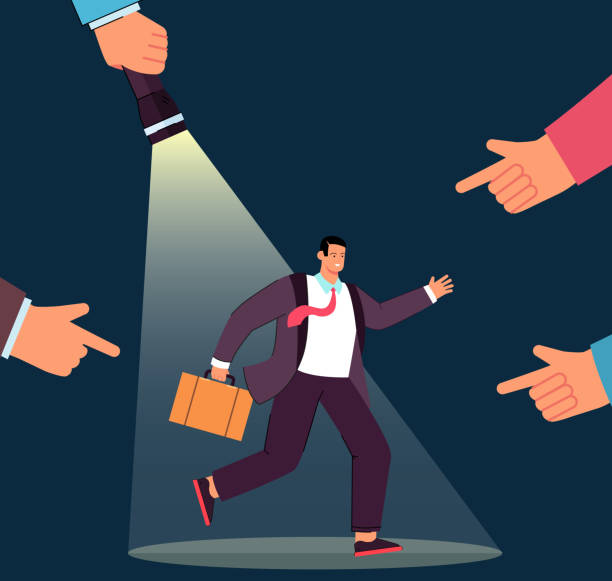 istock Fingers pointing at cartoon businessman in spotlight 1376417494