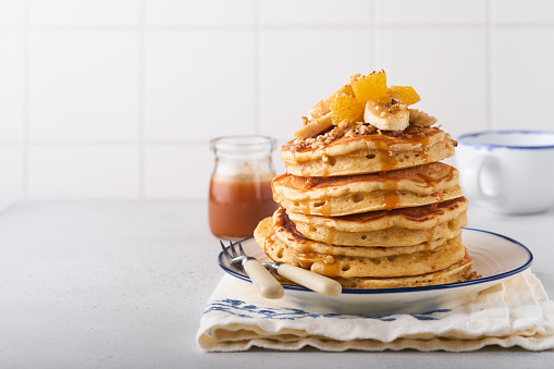 Pancakes. Homemade fluffy pancake with banana, walnut and caramel for breakfast on light concrete background. Delicious pancakes for traditional American breakfast. Selective focus. Mock up.