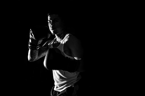 Young man practicing shadow boxing. Black and white high contrast image. Strenght and motivation.