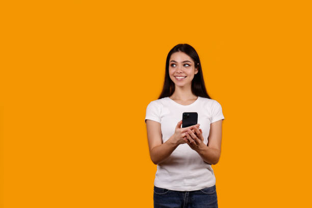 istock Young woman with a phone on yellow background. 1376442143