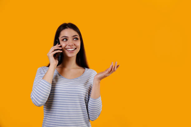 istock Young woman with a phone on yellow background. 1376444234