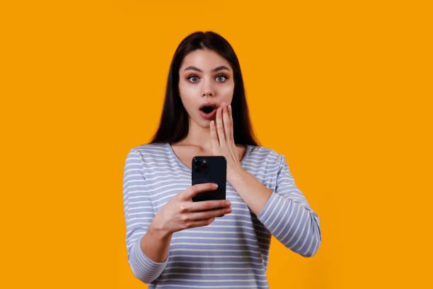 istock Young woman with a phone on yellow background. 1376444244