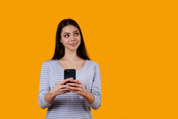 istock Young woman with a phone on yellow background. 1376444773