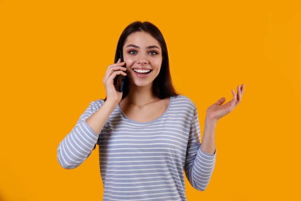 istock Young woman with a phone on yellow background. 1376459094